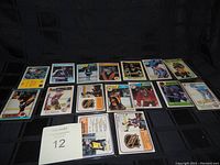 15 hockey cards from the 1980s arranged in two rows on a black surface, each in protective sleeves showing various players in NHL team uniforms.