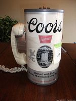 Front view of collectable phone shaped like Coors beer can showing branding and handset.