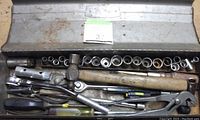 Top-down view of the open toolbox showing socket set, hammer, screwdrivers, pliers, and ratchets inside.