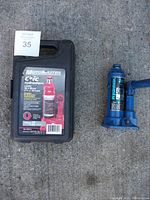 Two hydraulic bottle jacks side by side on the ground, one in black plastic case with Motomaster CRIC label and one blue jack with lever.