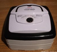 Closed view of Nesco food dehydrator top lid and motor base with control knob and temperature chart