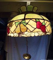 Full view of the stained glass hanging lamp illuminated and showing apple and pear fruit designs with green leaves.