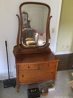 Front view of antique oak dresser with attached curved mirror reflecting a room.