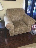 Front view of armchair showing patterned upholstery, cushioned seat and backrest, and arm style.