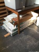 Three unopened boxes of CGC Designer Series 490 Adobe fire resistant ceiling panels stacked under a table