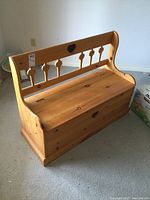 Front angled view of solid pine deacons bench with decorative heart cut-out on backrest and hinged storage seat.