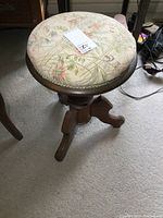 Top view of round cushioned seat with floral patterned upholstery and auction tag.