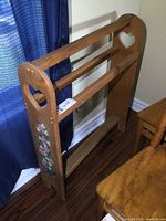 Full view of the wooden quilt rack showing heart cutouts on side panels and floral painting on one end.
