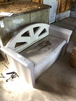 Side angle showing the storage bench, highlighting the armrest and part of the backrest with triangular cutouts, visible dirt and wear.