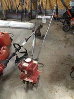 Full front view showing engine housing, handlebars and tines