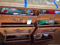 Two wooden drawers partially open revealing various kitchenware including glasses, cutlery, and bowls.