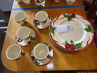 7 stacked Franciscan Apple dinner plates, 6 cups, and 6 saucers arranged on table.