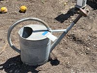 Side view showing full watering can, long spout with removable rose, and rounded handle on top.