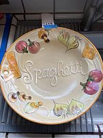Top view showing the full bowl with colorful painted vegetables and 'Spaghetti' embossed in center.