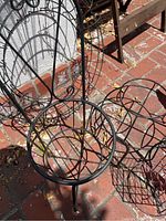 Top view of three metal plant stands showing wire baskets and circular frames with outdoor weathering