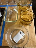 Photo of amber round baking dishes and clear rectangular glass loaf pans on a wooden surface.