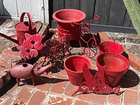 Photo showing all pots and metal garden decor items together on brick surface.