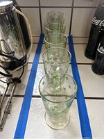 Six Irish coffee glasses lined in a row on a tiled kitchen counter, showing overall size and design.