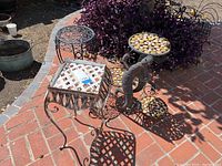 Wide view showing all three outdoor plant stands on brick patio with some surrounding plants and garden items.