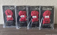 Four unopened Disney nuiMos Women Change The World outfits in original packaging, showing the back of the packaging with the red hoodie and black pants design.