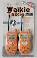 Front view of the packaging with two orange kids walkie talkies inside, visible keypad, speaker, and LED screen showing LCD display, antenna at the top.