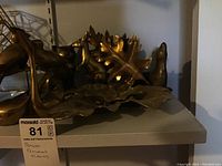 Photo of brass kangaroo, seal, and three brass leaves on shelf.