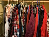 Closet rod view of multiple women's clothing items including tops, skirts, pants, dresses in an assortment of colors and patterns