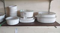 17-piece set of CorningWare French White dishes including round and rectangular casserole dishes and soufflé cups, some dishes have clear glass lids.