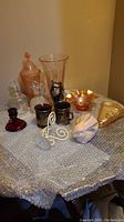Overview of assorted glassware items including ruby candle holder, carnival glass bowl, crystal decanter, glass cups, and decorative pieces.