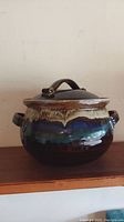 Full side view of the ceramic bean pot with lid showing glaze colors and handles.