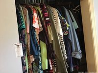 Wide view of multiple women's clothing items on hangers including tops and pants, various colors and patterns, size XL.