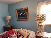 Room view showing two lamps positioned on side tables in a bedroom, both with mirrored bases and decorative metal shades with crystal details.