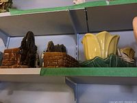 Shelf view showing brown brick water-wheel planter and yellow petal-lobe pot