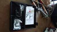 Ruger Mark III carrying case open showing empty molded plastic interior, owner's manual with Ruger logo visible, and packaged accessories.