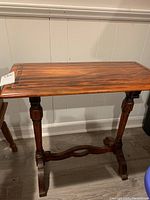 Front view of wooden side table showing rectangular top with wood grain and fluted legs with stretcher bar below.