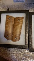 Pair of pistol grips with light brown curly grain wood finish in presentation box on bubble wrap