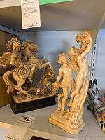 Side view of both statues together on shelf showing size and details