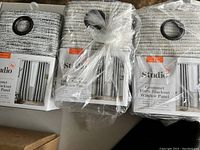 Three brand new Studio 3B blackout curtains with grommet holes for hanging, neatly packaged, modern grey texture.