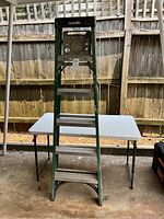 Front view of the 6 foot green Husky step ladder showing four steps and black platform top.