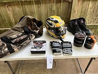Overview of all items on table: duffle bag, helmet, boots, boxing gloves, exercise wheel in box, Jetboil cooking system and fuel canister