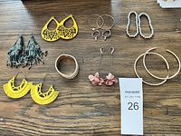Multiple assorted earrings and bracelets arranged on a wooden surface showing all items in the lot.
