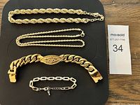 Overview of all four gold-tone chain jewelry pieces laid out on black background