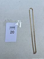 Full view of gold-tone curb chain necklace laid flat with lot tag