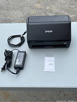 Epson ES-500W scanner with power adapter and power cord on table, front closed view