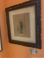Full view of the framed print hanging on a wall with ornate dark wood frame and wide cream mat.