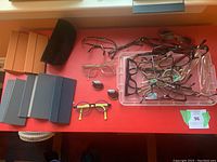 Overview of multiple eyeglass frames, sunglass lenses and storage sleeves on red surface