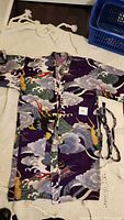 Full laid out view of the purple dragon print kimono with matching sash on a white textured background.