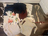 Overview of all clothing items arranged on a crocheted blanket, shows seven different pieces including tops and skirts in a range of colors and prints.