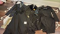 Full view of multiple black and cream-colored women's clothing items spread out showing variety of blazers, jackets, dress, and pants.