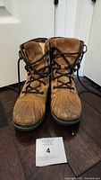 Pair of tan women's Ugg waterproof boots size 6 with brown laces shown from front, lightly used condition